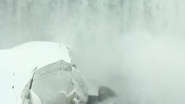 View of Niagara Falls pouring into the Niagara River during a very cold winter in February 2014, with layers of ice and heavy snow build up. Border between Canada and the United States.
