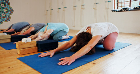 Group, elderly and people stretching in yoga class for fitness, exercise and spiritual wellness. Senior women, warm up and childs pose of pilates lesson, community and holistic balance at health club