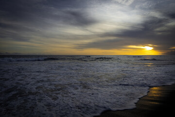 Breathtaking sunset at Bali. Bright sunrise sky against wavy ocean and palm trees, Bali, Indinesia
