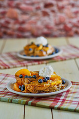 peach French toast topped with fresh blueberries and whipped cream on a striped red napkin