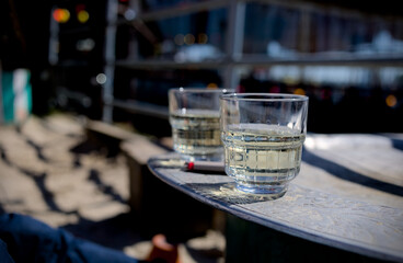 Two glasses of white wine on a table in a bar with sunshine and lights in the background