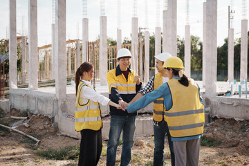 A team of engineers wearing hard hats inspect construction and inspect the site to ensure quality...