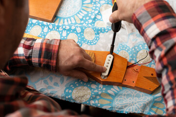 The guitar master screws the pickup to the slide guitar