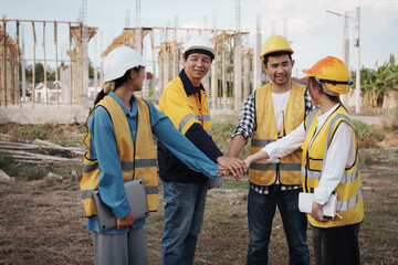 A team of engineers wearing hard hats inspect construction and inspect the site to ensure quality...