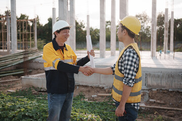 A team of engineers wearing hard hats inspect construction and inspect the site to ensure quality...