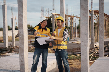 A team of engineers wearing hard hats inspect construction and inspect the site to ensure quality...