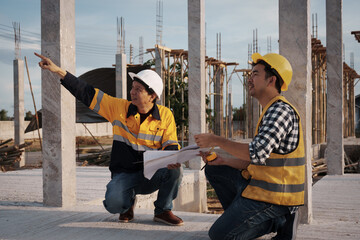 A team of engineers wearing hard hats inspect construction and inspect the site to ensure quality...