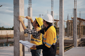 A team of engineers wearing hard hats inspect construction and inspect the site to ensure quality...