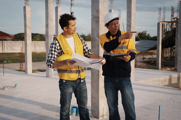 A team of engineers wearing hard hats inspect construction and inspect the site to ensure quality...