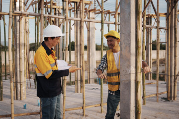 A team of engineers wearing hard hats inspect construction and inspect the site to ensure quality...