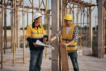 A team of engineers wearing hard hats inspect construction and inspect the site to ensure quality...
