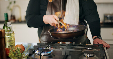 Cooking, flame and man in kitchen, hands and frying pan with food, wellness and ingredients. Closeup, person and chef with utensils, fire or meal prep with nutrition, culinary skills or flambe expert