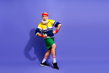 Naklejka premium Energetic senior man in retro sportswear striking a funny pose on a vibrant background showing lively spirit and vitality
