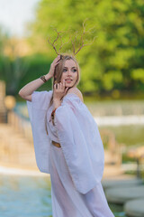 Beautiful girl with long hair and horns in a white dress