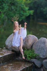 Beautiful girl with long hair and horns in a white dress