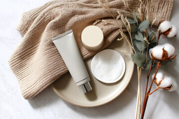 Soft textures and natural elements create a serene display of skincare products on a neutral background