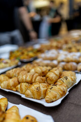 Variety of freshly baked pastries arranged on platters at a festive gathering in a warm atmosphere