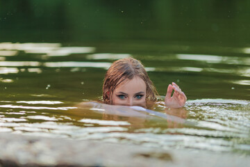 Fototapeta premium Beautiful Girl with long hair swims and dances in water