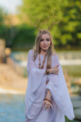 Beautiful girl with long hair and horns in a white dress