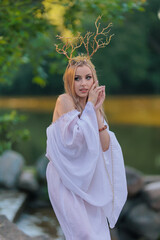 Beautiful girl with long hair and horns in a white dress
