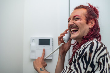 Non-binary person laughing while using intercom at home