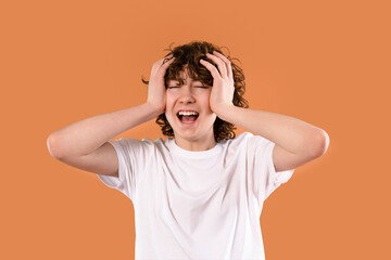 Expressing intense emotions, a young person with curly hair experiences frustration against a...