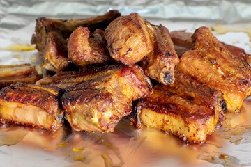 Grilled pork ribs served in foil. The ribs are golden brown, crispy on the outside and juicy on the inside, with a delicious texture. Close-up