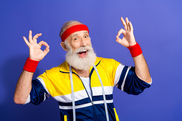Cheerful man in retro activewear enthusiastically gesturing okay while posing with a vibrant and...
