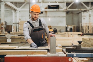 Carpenter working with wood plank and precision saw in factory for modular building