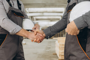 Construction workers shaking hands in modular building factory