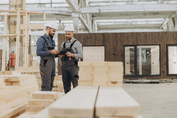Construction workers using digital tablet in modular building factory