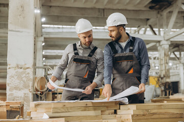 Fototapeta premium Construction workers examining blueprint in timber factory