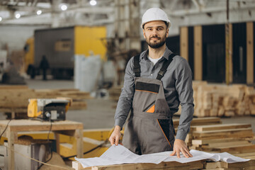 Construction worker analyzing blueprint in modular building factory