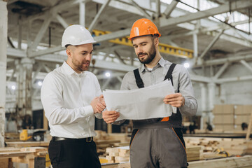 Engineers analyzing blueprint in modular building factory
