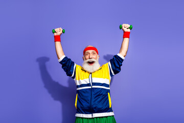 Cheerful man in retro sportswear enthusiastically exercising with dumbbells against a vibrant...
