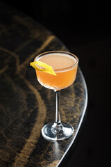 Peach Citrus Cocktail – Delicate peach-orange drink in a coupe glass, garnished with a lemon twist. Elegant and refreshing with a smooth, slightly tangy finish, perfect for a refined setting.