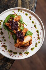Crispy Chicken Toast with Caramelized Onion – Rustic toast topped with fresh greens, sliced crispy chicken breast, and sweet caramelized red onions, garnished with herb oil.
