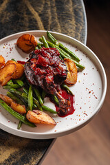 Duck Leg with Berry Sauce – Tender roasted duck leg topped with rich berry reduction, served with golden baby potatoes and sautéed green beans.
