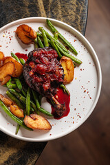 Duck Leg with Berry Sauce – Tender roasted duck leg topped with rich berry reduction, served with golden baby potatoes and sautéed green beans.
