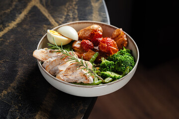 Grilled Chicken Bowl with Vegetables – A wholesome bowl with grilled chicken breast, roasted cherry tomatoes, baby potatoes, tender broccoli, asparagus, and a soft-boiled egg, garnished with rosemary.