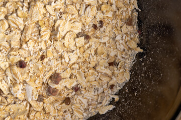black bowl of oatmeal porridge with dried berries and fruits, filled with instant oatmeal porridge with additives, closeup