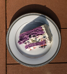 A piece of blueberry cake on a plate on a wooden background 
