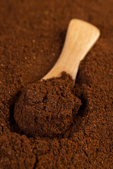 background of ground coffee and a small wooden spoon, a large number of roasted ground coffee beans in powder and a wooden spoon, close up