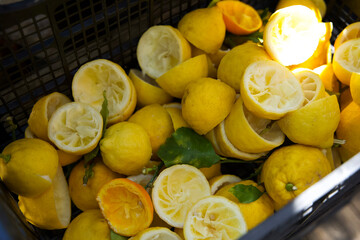 Freshly cut yellow lemons piled in a black basket, showcasing vibrant citrus fruit with some halves...