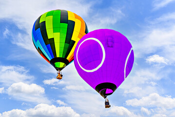 Colorful hot air balloon flying over blue sky with white clouds	