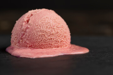 melting ice cream on a dark slate , sweet cold pink ice cream , close up