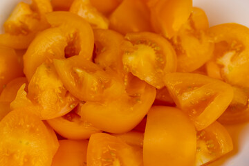 orange tomatoes cut into pieces of different sizes , clean washed tomatoes are sliced for salad preparation