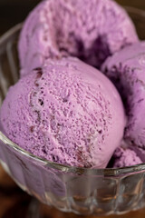 purple ice cream with blueberry flavor, blueberry ice cream balls in glass, The ice cream started to melt
