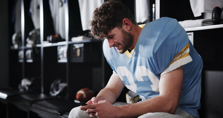 Football, player and man with phone in locker room for text message, check notifications and match break. Sports, athlete and relax with smartphone for social media scroll, online news or mobile chat