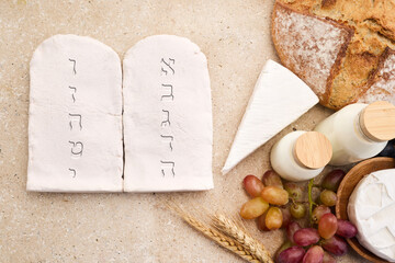 Happy Shavuot concept. Two Stones with Ten Commandments in Ancient Hebrew, Grains, milk and cheese